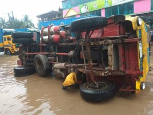 ভাঙা সড়কে উল্টে গেল ট্রাক